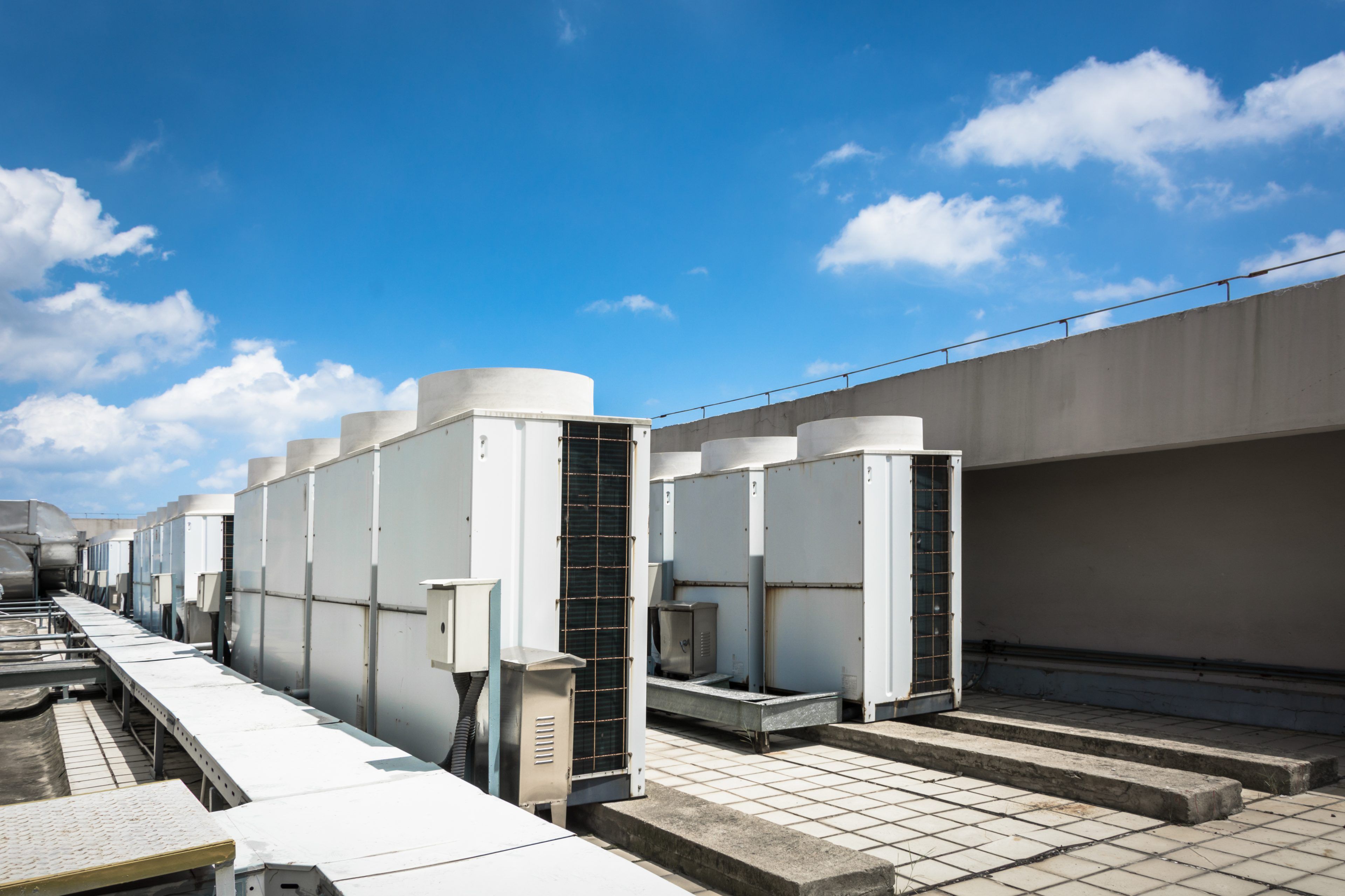 Air compressor machine part of air conditioner system on roof deck with sky background.